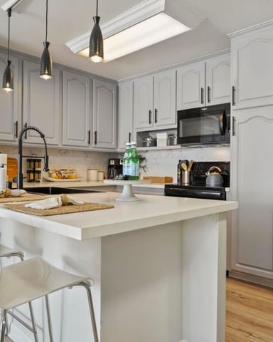 Modern kitchen with white cabinetry, stainless steel appliances, island with seating, and pendant lighting